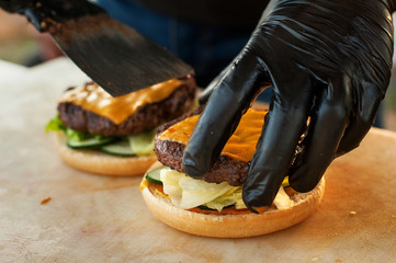 Chef making beef burger with cheese on open kitchen. Street fast food.