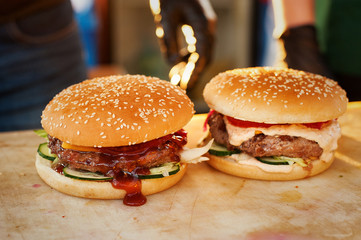Two finished burger on a wooden board. Open kitchen in the street. Street fast food