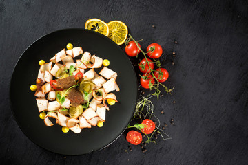 dish of many pieces of lard with vegetables on black background
