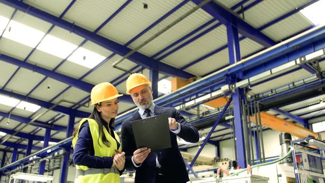 Industrial man and woman engineers with clipboard in a factory working.