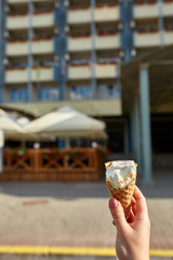 A first person view, a person walking along the road with an ice cream in her hands, shallow depth of field, vertical.