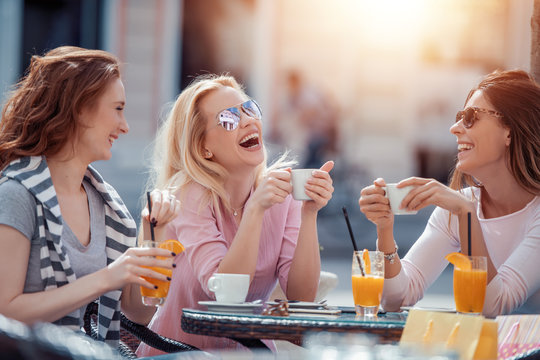Three happy young woman chatting in cafe
