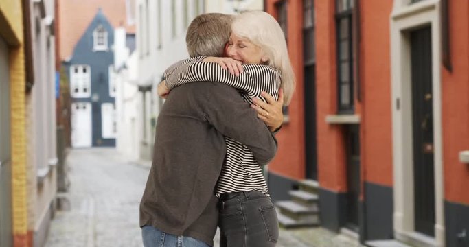 Mature couple holding keys to new home in Bruges, Playful husband carries his wife to their new home, 4k