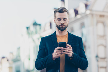 Portrait of smart concentrated man having smart phone cellphone in hands checking email searching contact using 5G internet over blurred background. Electronic wireless device apps concept
