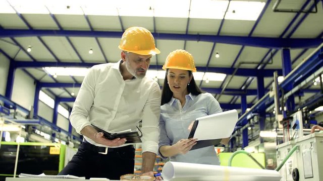 Industrial man and woman engineers with clipboard in a factory, working.