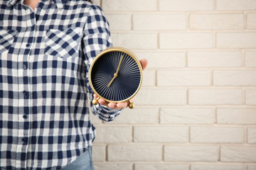 Woman holding clock near brick wall. Time management concept