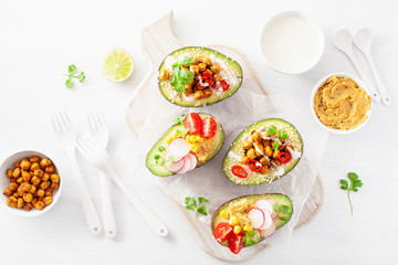 avocado boats stuffed with hummus, tomatoes, radish, roasted chickpea