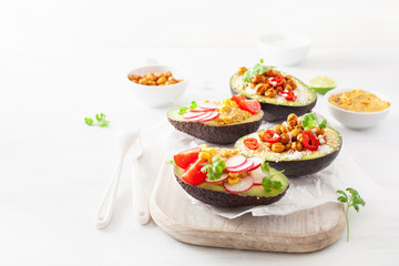 avocado boats stuffed with hummus, tomatoes, radish, roasted chickpea