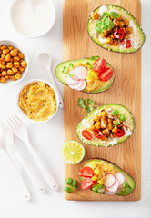 avocado boats stuffed with hummus, tomatoes, radish, roasted chickpea