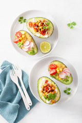 avocado boats stuffed with hummus, tomatoes, radish, roasted chickpea