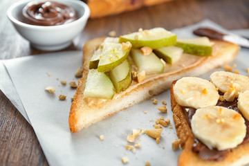 Tasty sweet toasts with fruits on wooden table