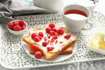 Tasty sweet toasts with raspberries and cup of tea on vintage tray