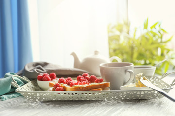 Vintage tray with tasty toasts and fresh raspberries on wooden table