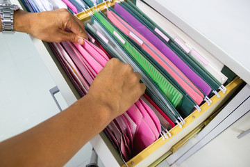 Man hands Search files document of hanging file folders in drawer in a whole pile of full papers, concept 
