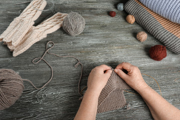 Senior woman knitting sweater at table