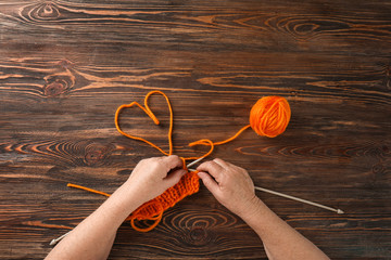 Senior woman knitting sweater at table