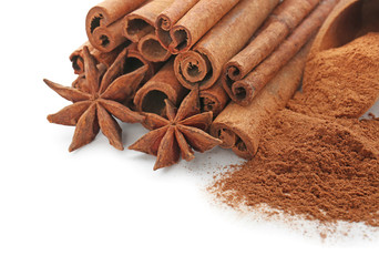 Cinnamon sticks with powder and anise stars on white background, closeup