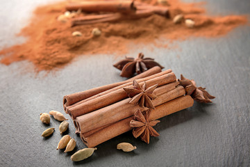 Composition with heap of cinnamon sticks and spices on grey background