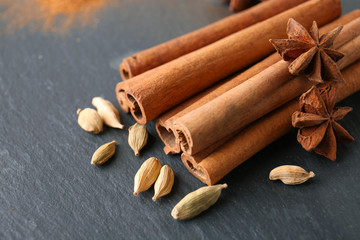 Heap of cinnamon sticks and spices on grey background, closeup