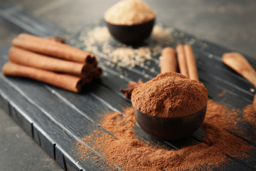 Bowl with cinnamon powder on wooden board
