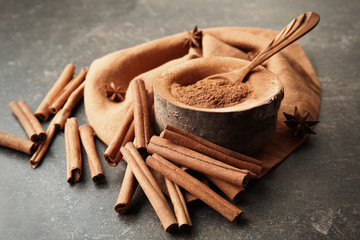 Composition with cinnamon powder and sticks on grey background