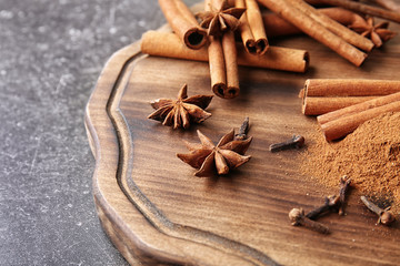 Composition with cinnamon and spices on wooden board, closeup