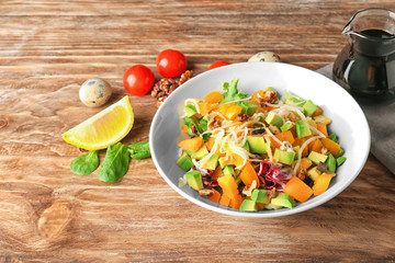 Plate of tasty salad with ripe avocado on wooden table