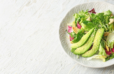 Plate of tasty salad with ripe avocado on table