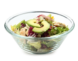 Glass bowl of tasty salad with ripe avocado on white background