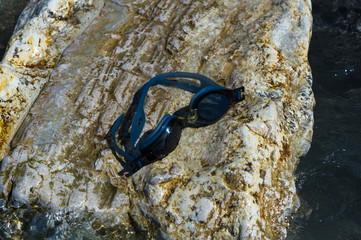 eyeglasses for swimming on a pebble beach in the sea waves