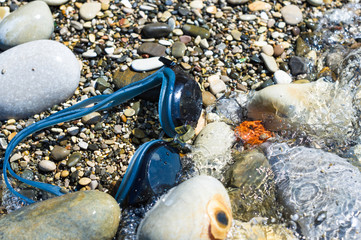 eyeglasses for swimming on a pebble beach in the sea waves