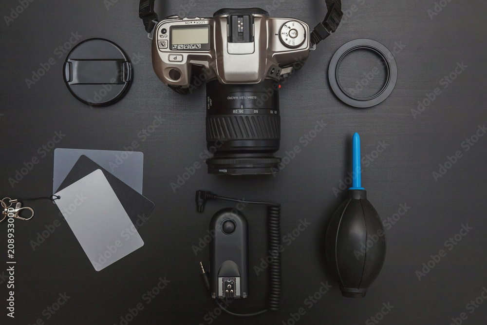 Wall mural Top view of work space photographer with dslr camera system, camera cleaning kit, lens and camera accessory on black table background. Hobby journalism photography technology art concept