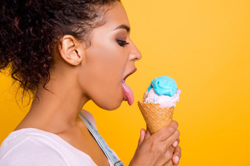 Profile half-face portrait of sensual naughty girl licking ice cream in waffle cone with tongue out...