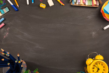 bright office supplies, yellow alarm clock on black chalkboard top view, copy space. concept: back to school, school's out, school holidays, teacher's day