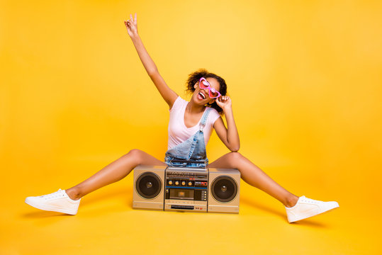 Portrait of fancy crazy girl in eyewear sneakers gesturing v-sign having boom box with cassette tape enjoying stereo sound. Party time music lover fan concept