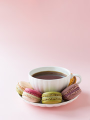 Beautiful cup of coffee and macaroons on the pink background