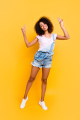 Fototapeta na wymiar Vertical portrait of fullbody portrait of cool peaceful chick with beaming smile gesturing v-signs with two hands looking at camera isolated on yellow background
