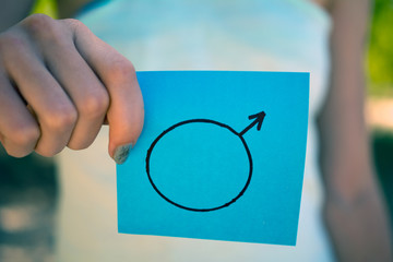 gender stereotypes concept, a piece of paper with  male symbol in a woman's hand