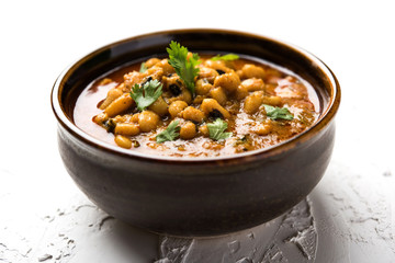 Black Eyed Kidney Beans Curry or Chawli chi usal / Barbati masala, served in a ceramic bowl over moody background, selective focus
