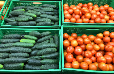 Many a red tomatoes with cucumbers in a boxes