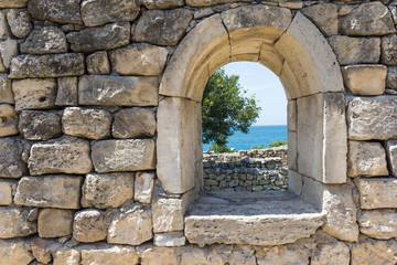 Fototapeta na wymiar wall with a window in the ruins of an ancient city overlooking the sea, selective focus