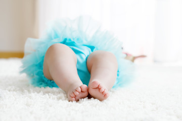 Close up of legs and feet of baby girl on white background wearing turquoise tutu skirt. © Irina Schmidt