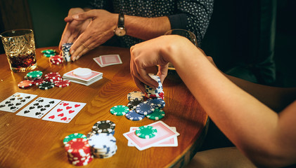 Side view photo of friends sitting at wooden table. Friends having fun while playing board game.