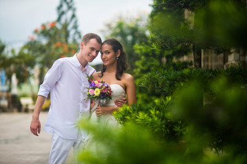 a wedding couple, a beautiful young bride and groom, are standing in the Park outdoors, embracing and and smiling