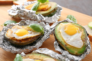 Eggs baked in avocado on wooden board, closeup