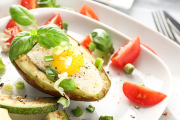 Tasty baked avocado with egg and fresh vegetables on plate, closeup