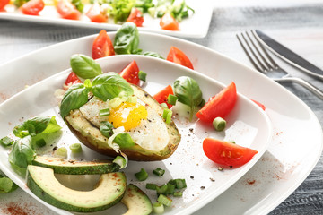 Tasty baked avocado with egg and fresh vegetables on plate, closeup