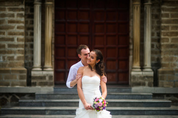 Naklejka premium The groom kisses the bride against the Catholic Church