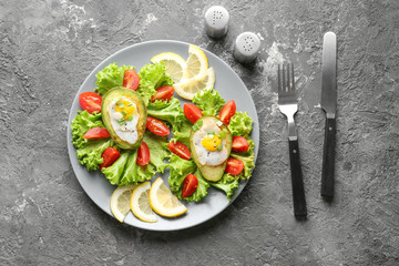Plate with eggs baked in avocado and fresh vegetables on table