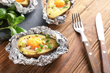 Avocado baked with egg in foil on wooden table